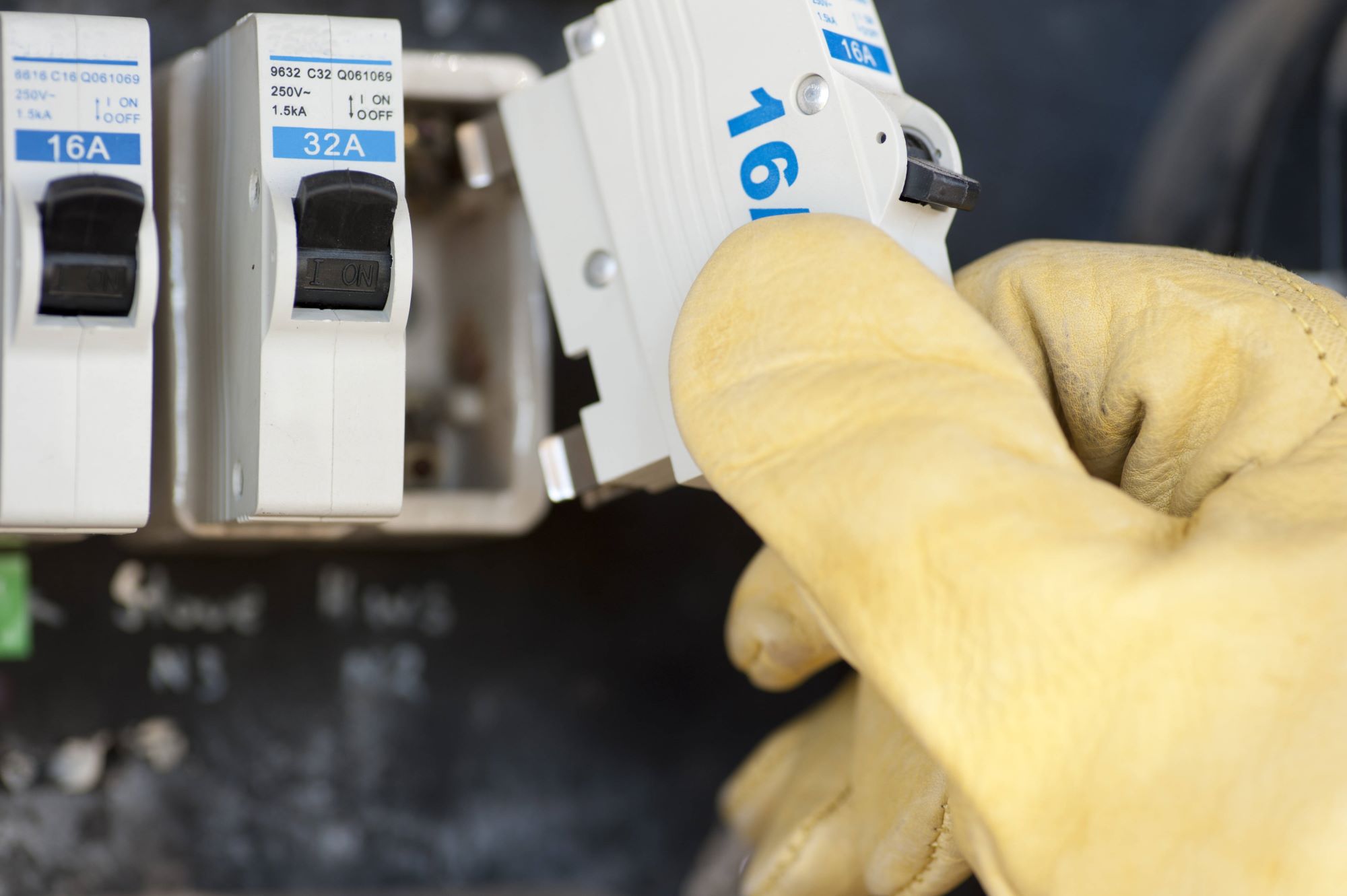 Close up of gloved hand removing or replacing a fuse in a switchboard