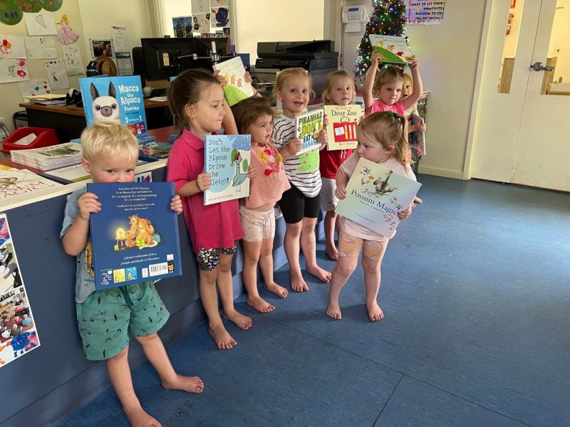 Eight children lined up on an angle each holding a story book