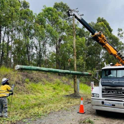 Crews standing around a vehicle with a power pole to lift to ground