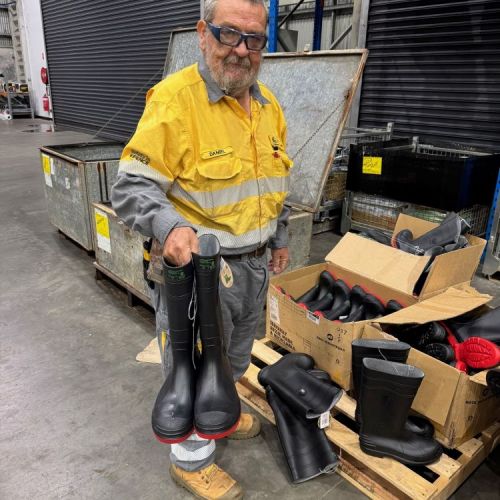 A worker holding a pair of wellies rain boots in a depot