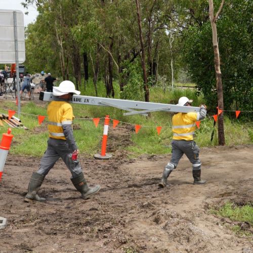 Two crew members carry a pole at Ollera Creek