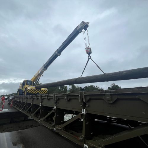 Ollera Creek north side pole being moved across the temporary bridge