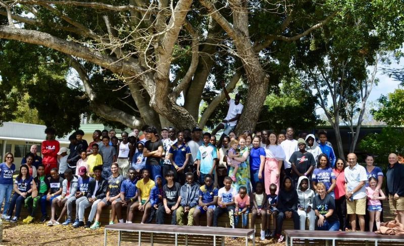 large group photo of 30 students from overseas posing under a tree