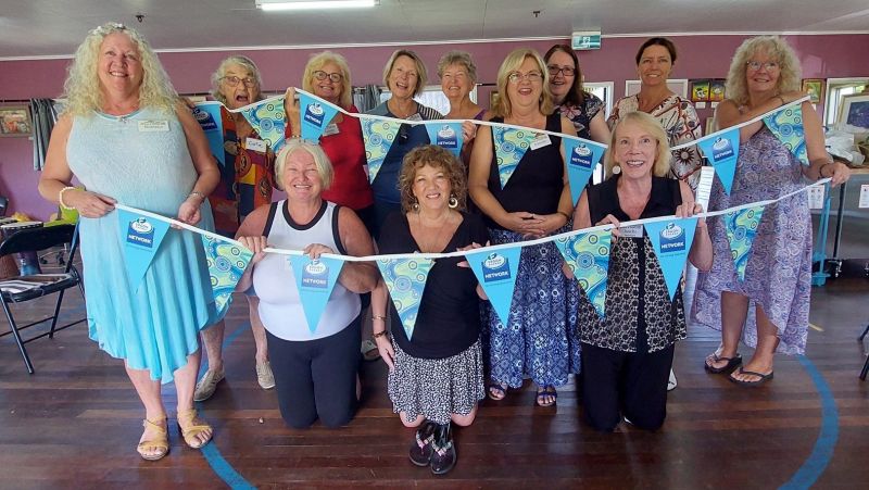 Members lined up in club house smiling and holding Ergon Bunting