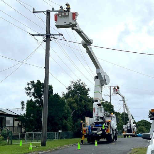 Field crews working cherry picker on powerlines in a street