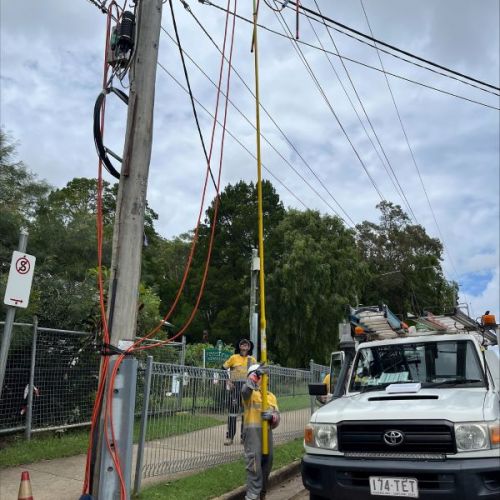 Crews with a yellow pole next to car working on powerlines