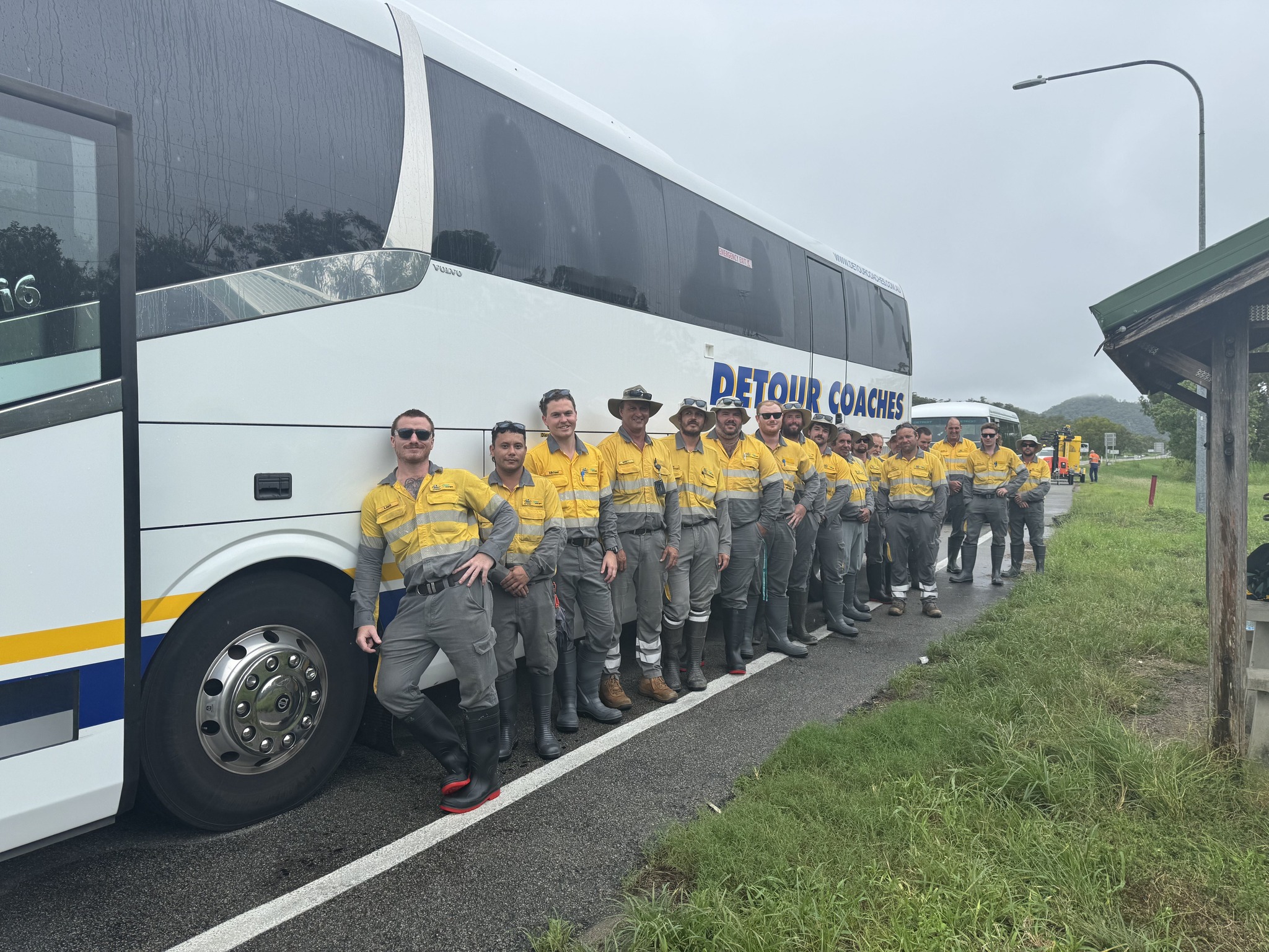  A number of crew members lined up against a coach on the road