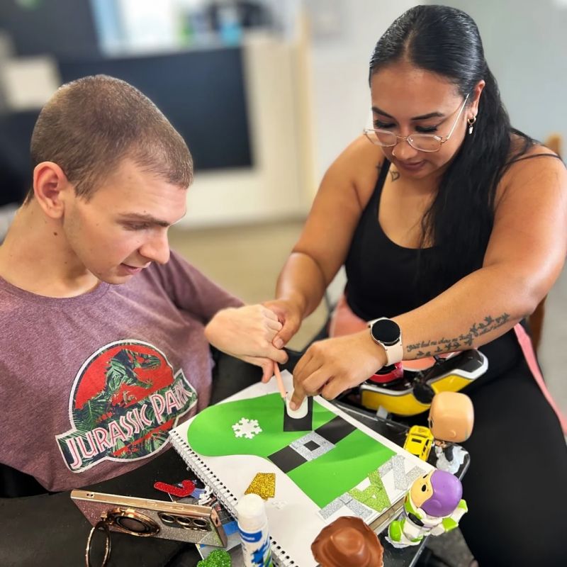 Woman helping man in a wheelchair with a puzzle