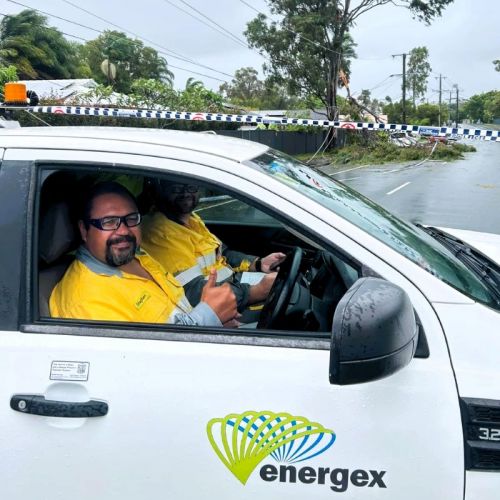 Crews in a work vehicle with trees in powerlines on road