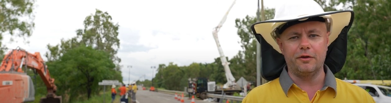 Crew member on road in front of helicopter with powerlines