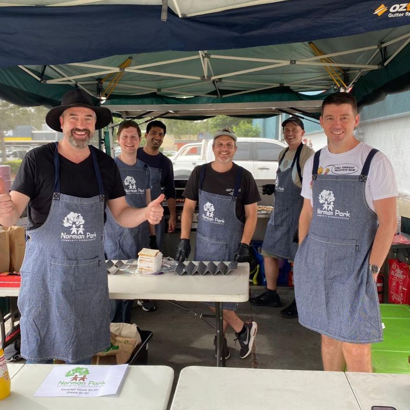 Dads in aprons cooking sausages at Bunnings