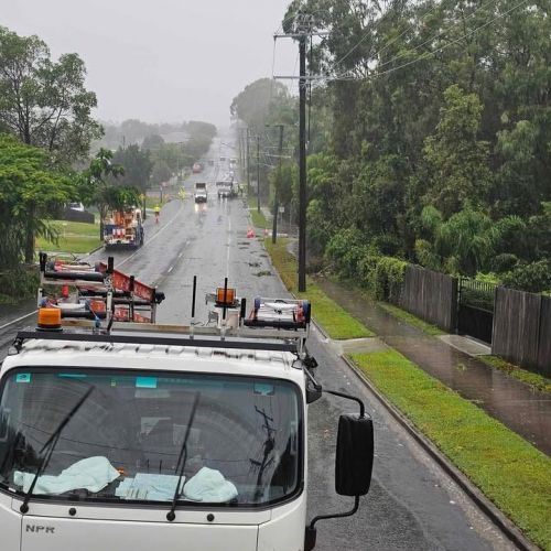 A number of work vehicles down a street making repairs