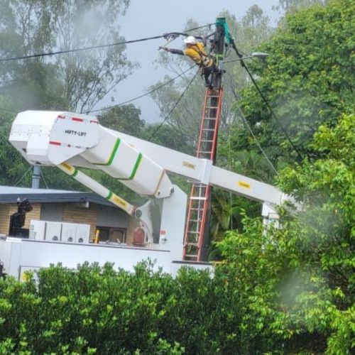 Crew member on a ladder up a power pole restoring power