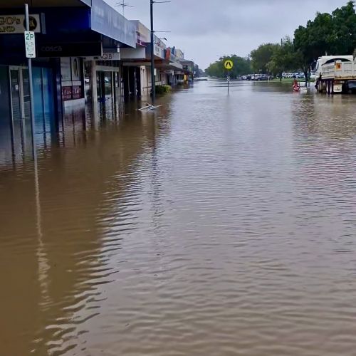 A flooded street with shops and cars