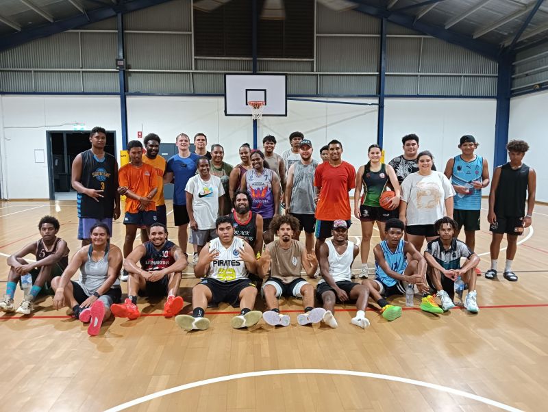 Basketball team posing in front of hoop on court