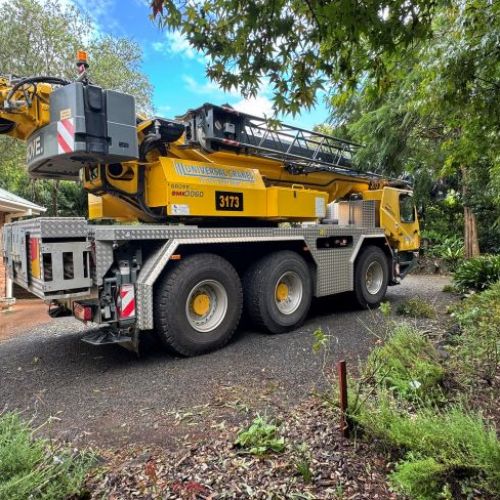 Big yellow crane truck in the driveway at residential house