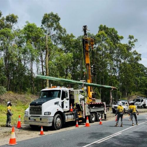 Crews standing around a vehicle with a power pole to lift to ground