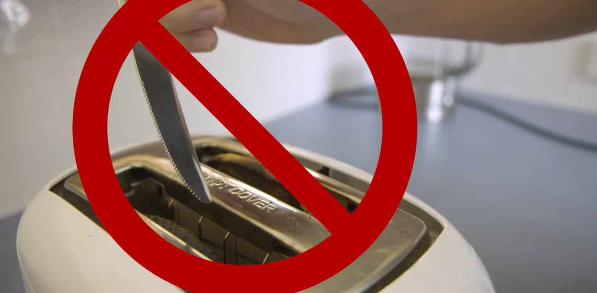 A toaster on a kitchen bench with a danger symbol