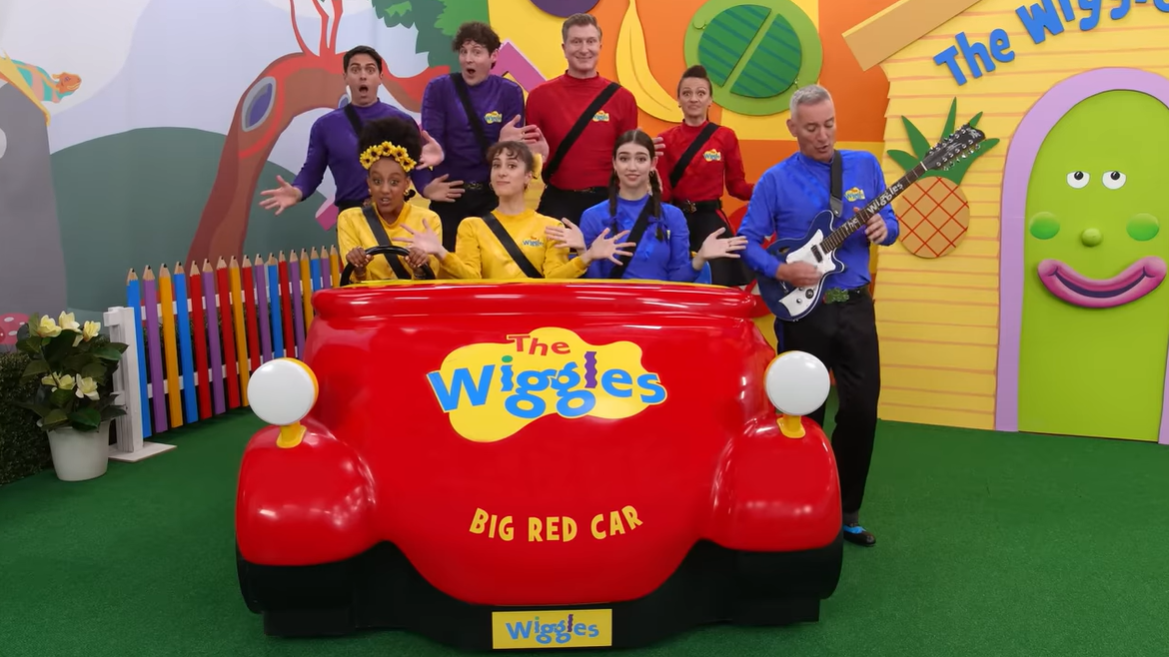 The Wiggles sitting in the Big Red Car singing