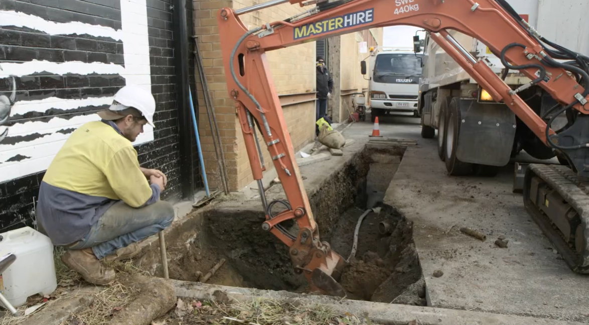 A digger and working digging up earth around underground powerlines