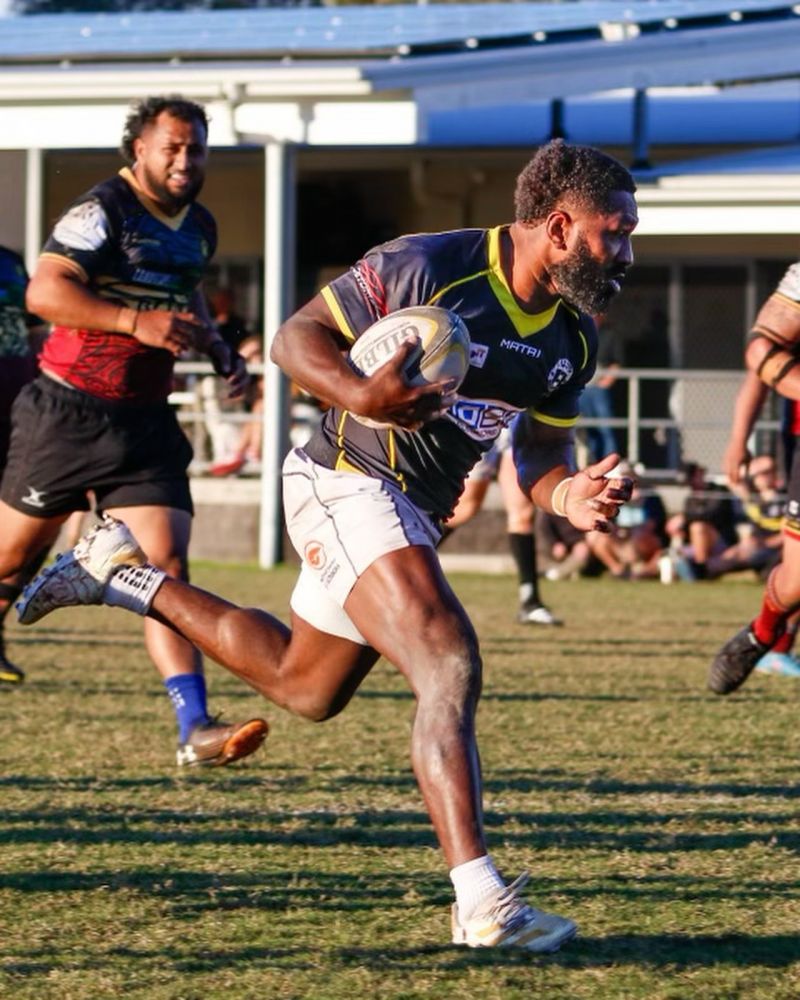 Man in white shorts and football jersey running with ball